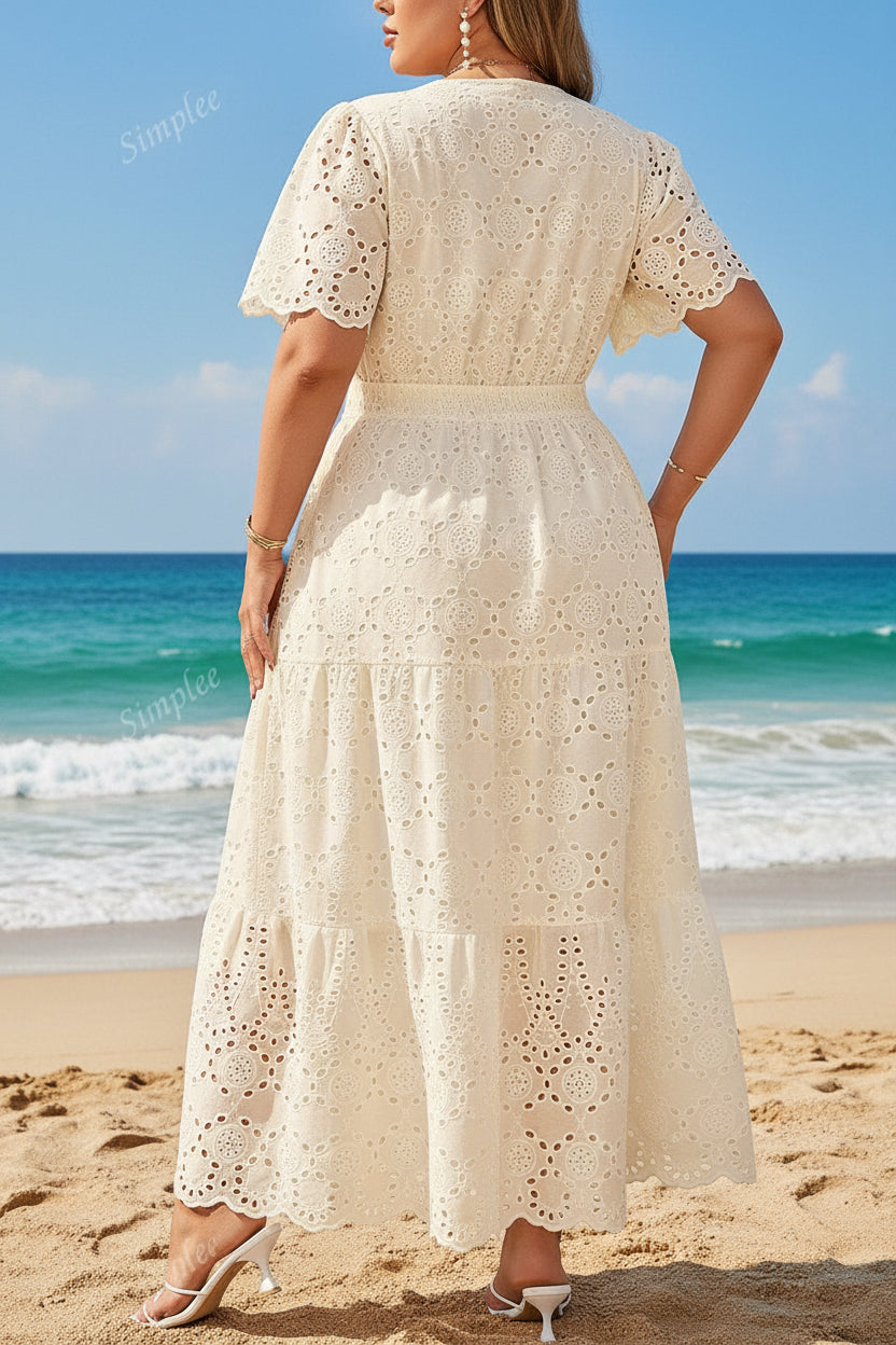 Woman wearing a white lace dress standing against a stone wall.