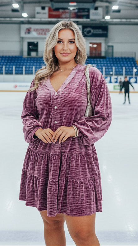 Woman in a pink dress standing on an ice rink with people in the background